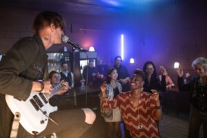 Man in Black Jacket Singing While Playing Guitar